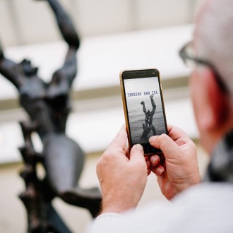 Man is looking at the Zadkine by the Sea app on his phone